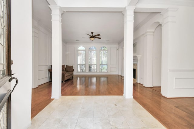 unfurnished living room with decorative columns, ceiling fan, crown molding, and light tile patterned flooring