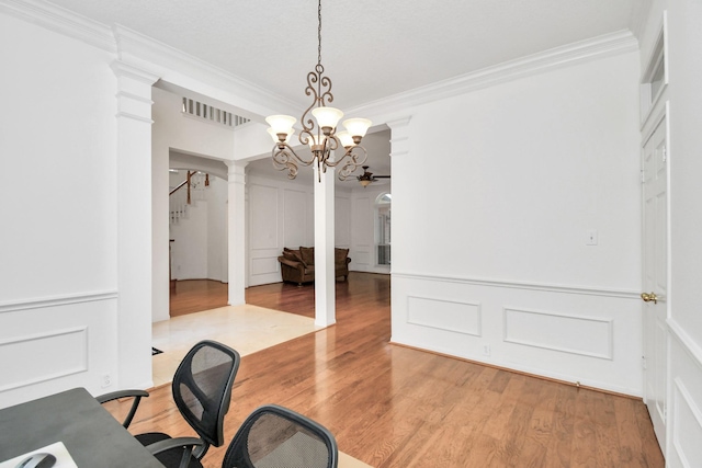 spacious closet featuring ornate columns, a chandelier, and light hardwood / wood-style floors