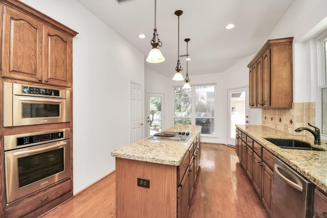 kitchen featuring light stone counters, stainless steel dishwasher, pendant lighting, black electric cooktop, and a kitchen island