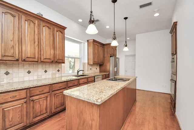 kitchen featuring pendant lighting, sink, light hardwood / wood-style flooring, a kitchen island, and stainless steel appliances