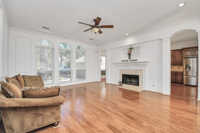 living room with decorative columns, ceiling fan, ornamental molding, and light hardwood / wood-style floors