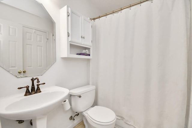 bathroom featuring toilet, walk in shower, and sink