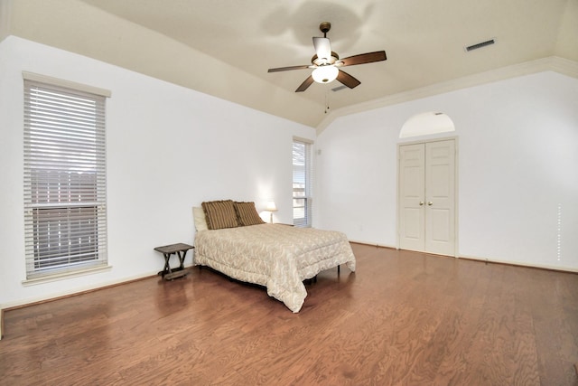 bedroom with ornamental molding, vaulted ceiling, ceiling fan, dark wood-type flooring, and a closet