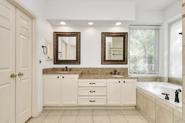 bathroom with tile patterned floors, vanity, and tiled tub