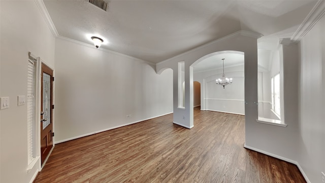 unfurnished living room featuring hardwood / wood-style floors, a notable chandelier, and ornamental molding