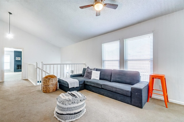 carpeted living room with a textured ceiling, vaulted ceiling, and ceiling fan