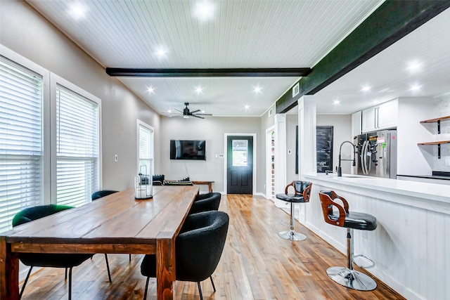 dining room with ceiling fan, light hardwood / wood-style flooring, beamed ceiling, and sink