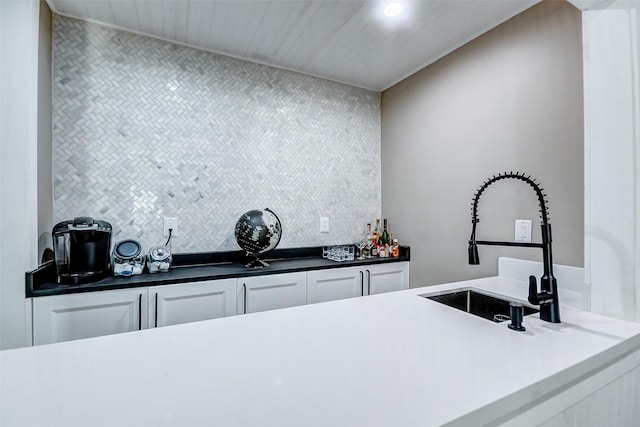 kitchen featuring white cabinets, backsplash, and sink