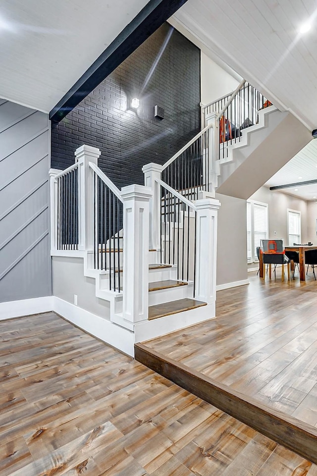 staircase featuring hardwood / wood-style flooring and beamed ceiling