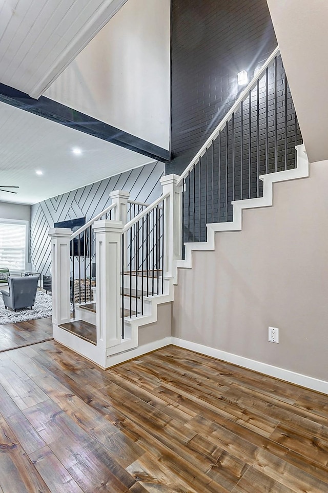 stairs with hardwood / wood-style flooring, beam ceiling, and a towering ceiling