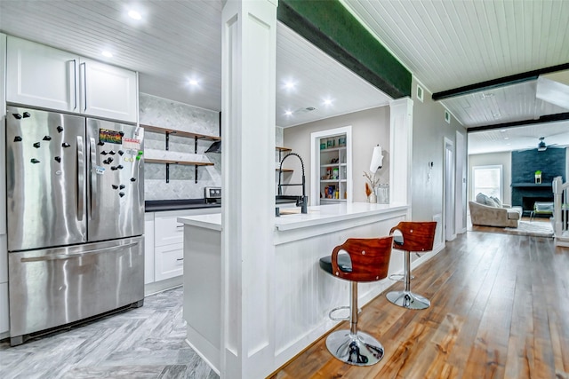 kitchen featuring light parquet floors, stainless steel fridge, and white cabinetry