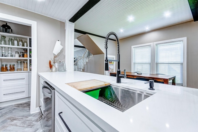 kitchen featuring stainless steel dishwasher, white cabinetry, and sink