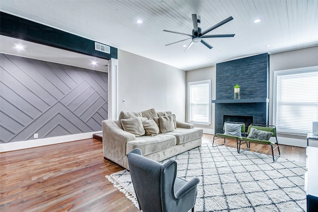 living room with ceiling fan, light wood-type flooring, a fireplace, and wooden ceiling