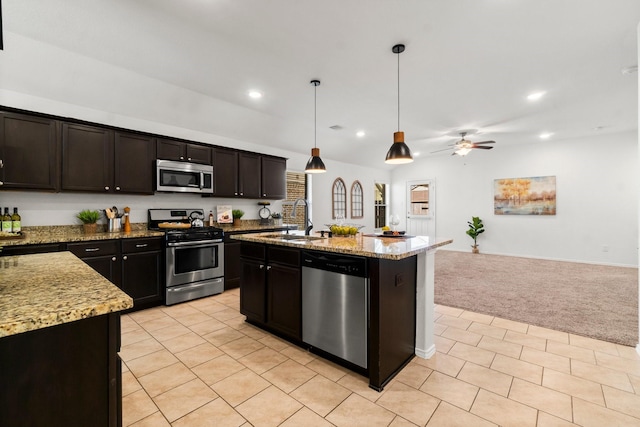 kitchen featuring light carpet, appliances with stainless steel finishes, sink, a center island with sink, and hanging light fixtures