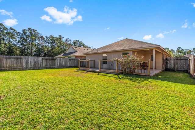 back of property with a wooden deck and a yard