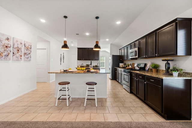 kitchen with appliances with stainless steel finishes, a center island, decorative light fixtures, and dark stone counters