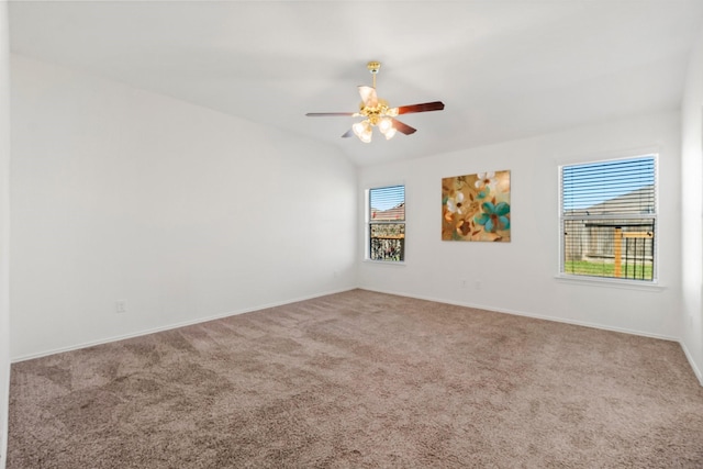 empty room with ceiling fan, plenty of natural light, carpet floors, and vaulted ceiling