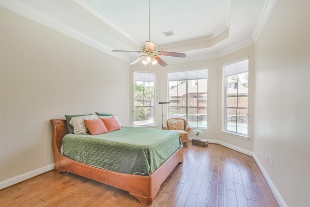 bedroom featuring hardwood / wood-style floors, ceiling fan, crown molding, and a tray ceiling