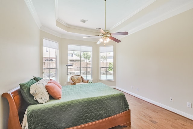 bedroom with hardwood / wood-style floors, ceiling fan, a raised ceiling, and ornamental molding