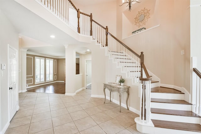 stairway with crown molding, tile patterned flooring, and a towering ceiling