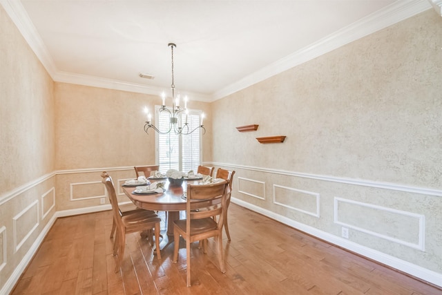 dining space with hardwood / wood-style floors, a notable chandelier, and crown molding