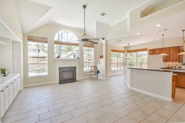 unfurnished living room featuring ceiling fan, a fireplace, light tile patterned floors, and lofted ceiling