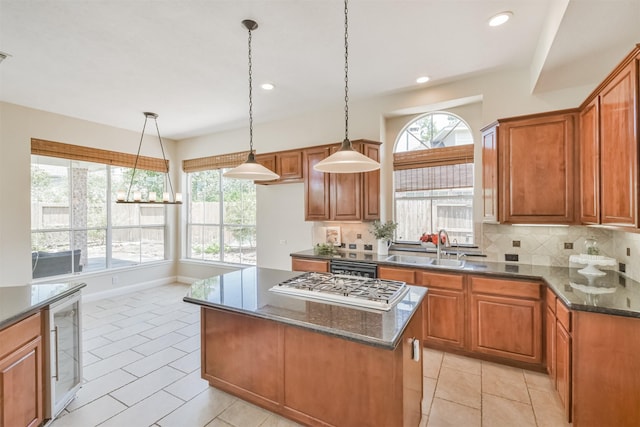 kitchen with a center island, sink, dark stone countertops, decorative backsplash, and light tile patterned floors