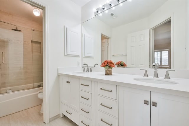 full bathroom featuring vanity, toilet, wood-type flooring, and combined bath / shower with glass door