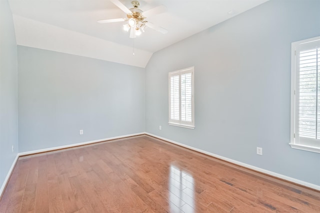 empty room featuring a wealth of natural light, ceiling fan, light hardwood / wood-style floors, and vaulted ceiling