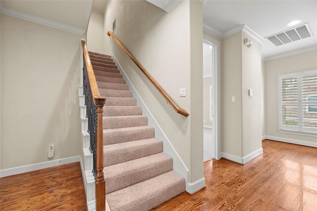 stairs featuring hardwood / wood-style floors and crown molding