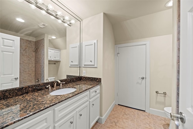 bathroom with tile patterned flooring, vanity, vaulted ceiling, and toilet