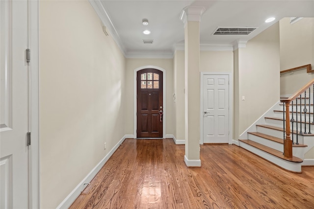 entrance foyer with wood-type flooring, crown molding, and decorative columns