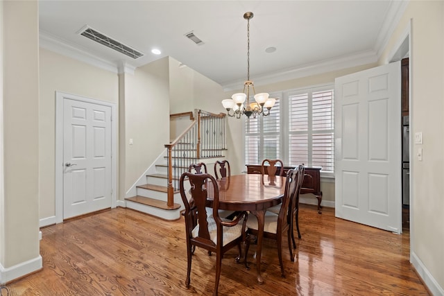 dining area featuring ornamental molding, a notable chandelier, and hardwood / wood-style flooring