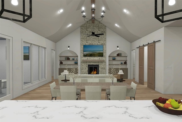 interior space featuring a kitchen bar, a barn door, high vaulted ceiling, built in features, and a stone fireplace