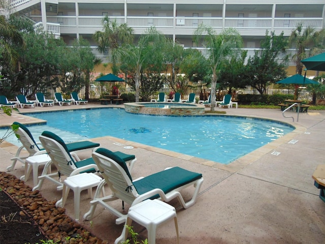 view of swimming pool featuring a hot tub and a patio