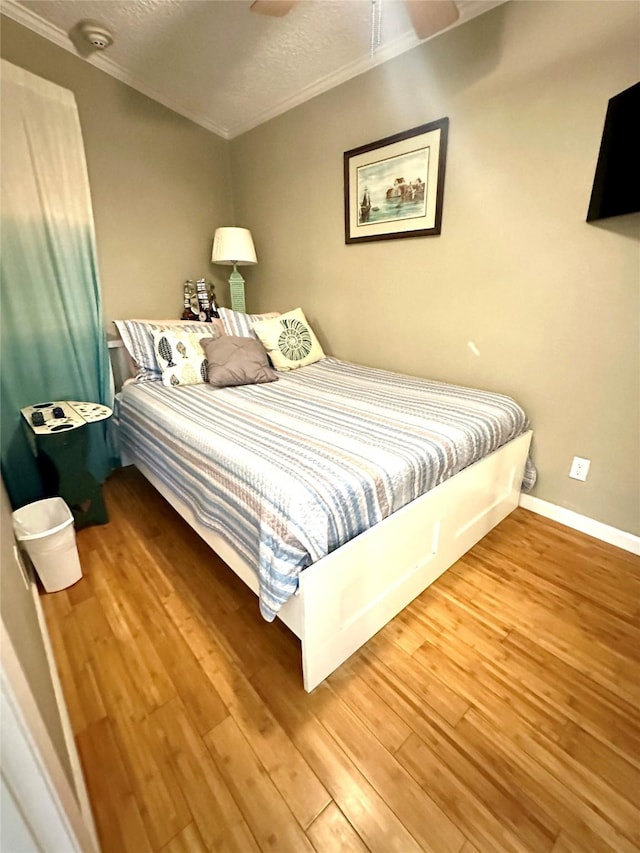 bedroom featuring hardwood / wood-style flooring, ornamental molding, and a textured ceiling