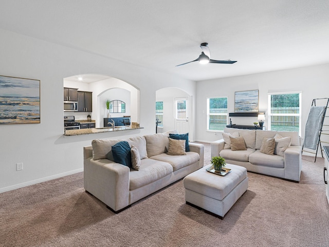 living room with ceiling fan, sink, and light carpet