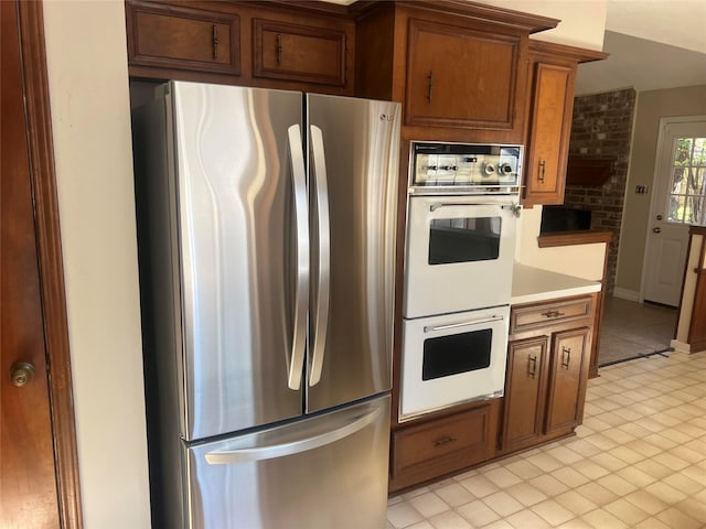 kitchen featuring double oven, stainless steel refrigerator, and brick wall