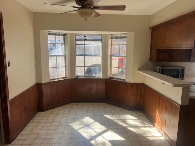 unfurnished dining area featuring wooden walls and ceiling fan