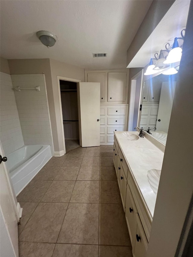 bathroom with tile patterned flooring, vanity, and tiled shower / bath