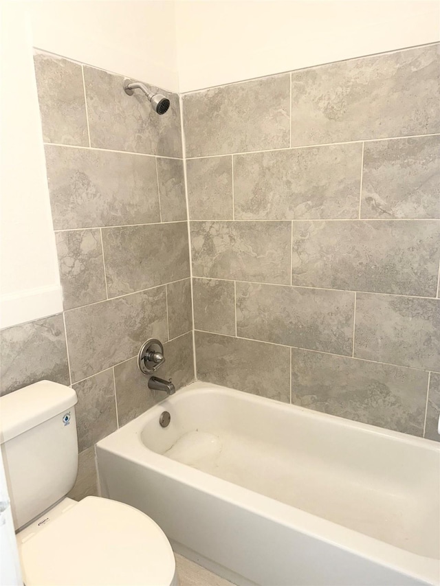 bathroom featuring toilet and tiled shower / bath