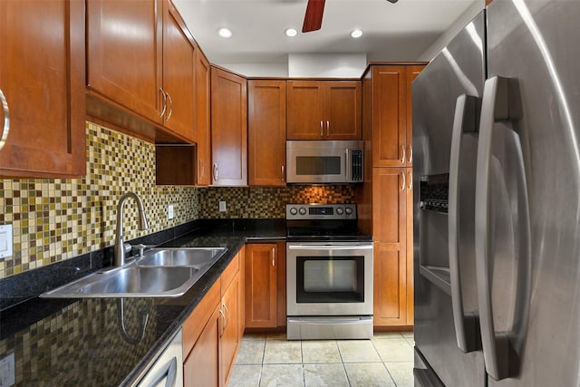 kitchen featuring decorative backsplash, appliances with stainless steel finishes, sink, light tile patterned floors, and dark stone countertops