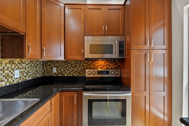 kitchen featuring sink, stainless steel appliances, tasteful backsplash, and dark stone countertops