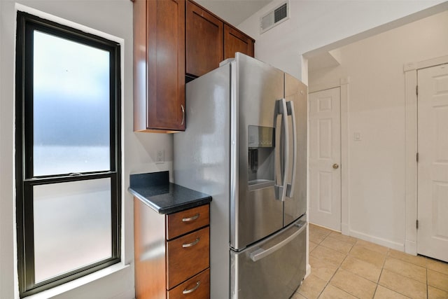 kitchen featuring stainless steel fridge, light tile patterned floors, and a healthy amount of sunlight