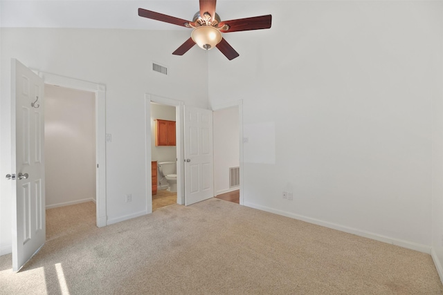 unfurnished bedroom featuring ceiling fan, light carpet, high vaulted ceiling, and ensuite bath