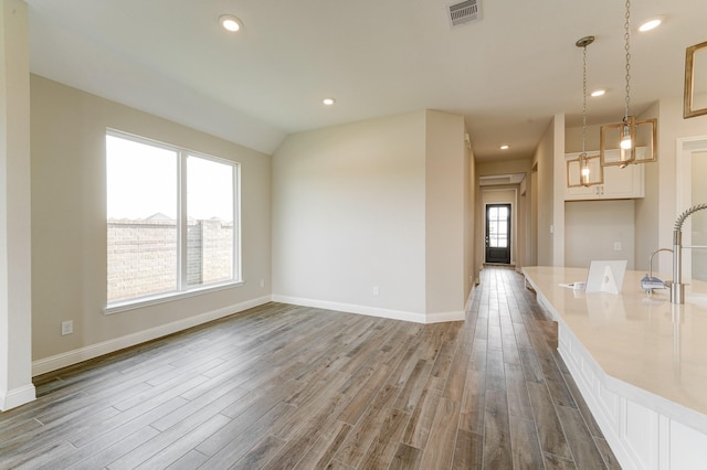 interior space featuring recessed lighting, wood finished floors, visible vents, baseboards, and vaulted ceiling