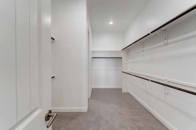 walk in closet featuring light colored carpet