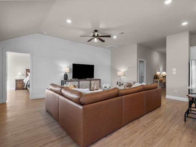 living room featuring ceiling fan, light hardwood / wood-style flooring, and vaulted ceiling