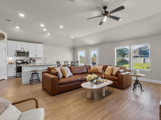 living room with light hardwood / wood-style floors, ceiling fan, lofted ceiling, and sink