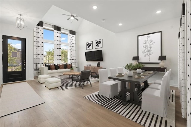 dining room featuring ceiling fan with notable chandelier, light hardwood / wood-style floors, a healthy amount of sunlight, and lofted ceiling